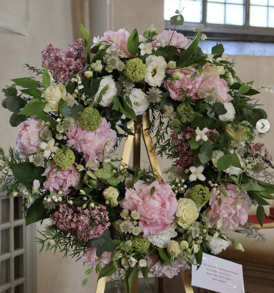 Stor blomsterkrans på stativ i kyrkomiljö